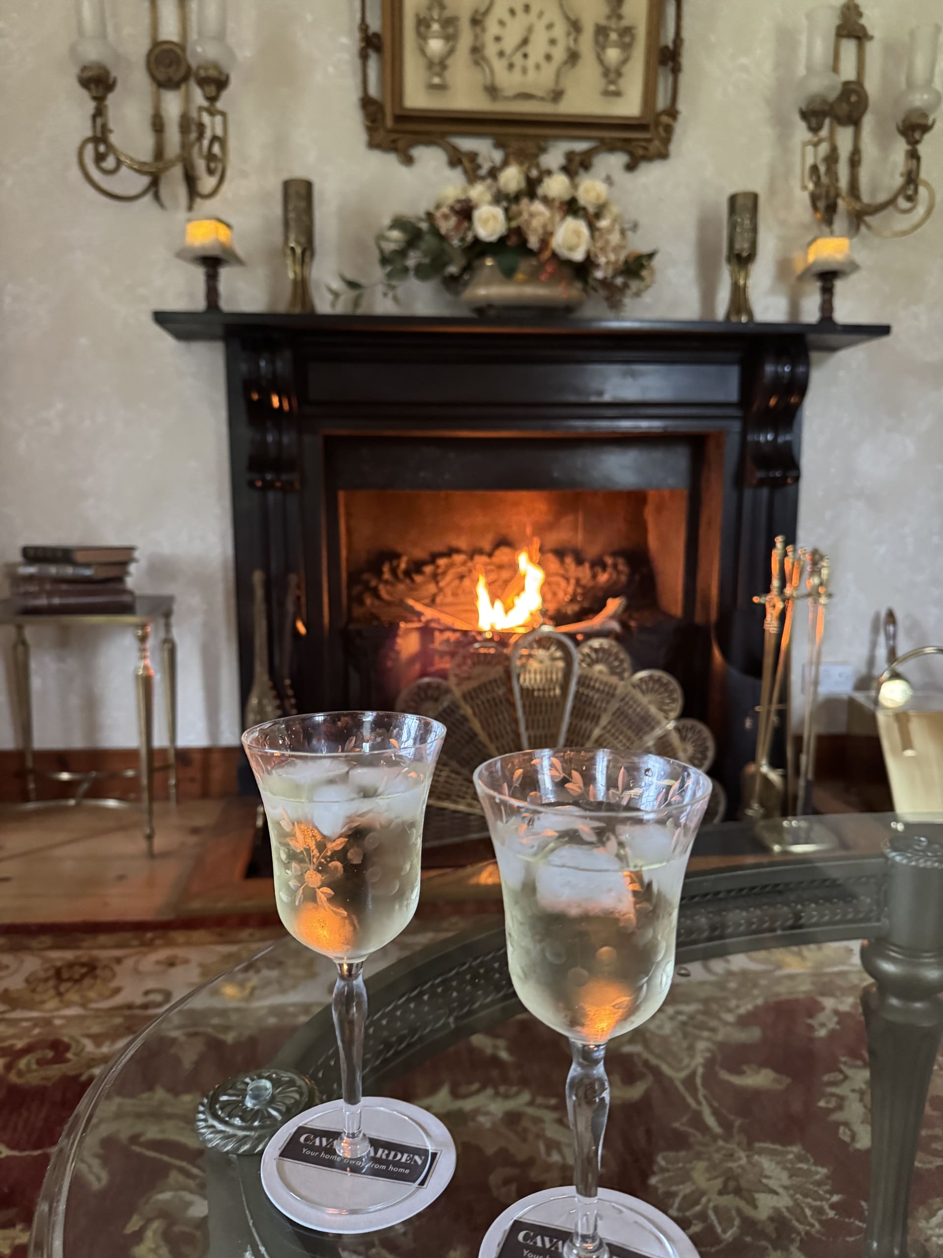 Two glasses of wine on a Cavangarden coaster in front of an open fire