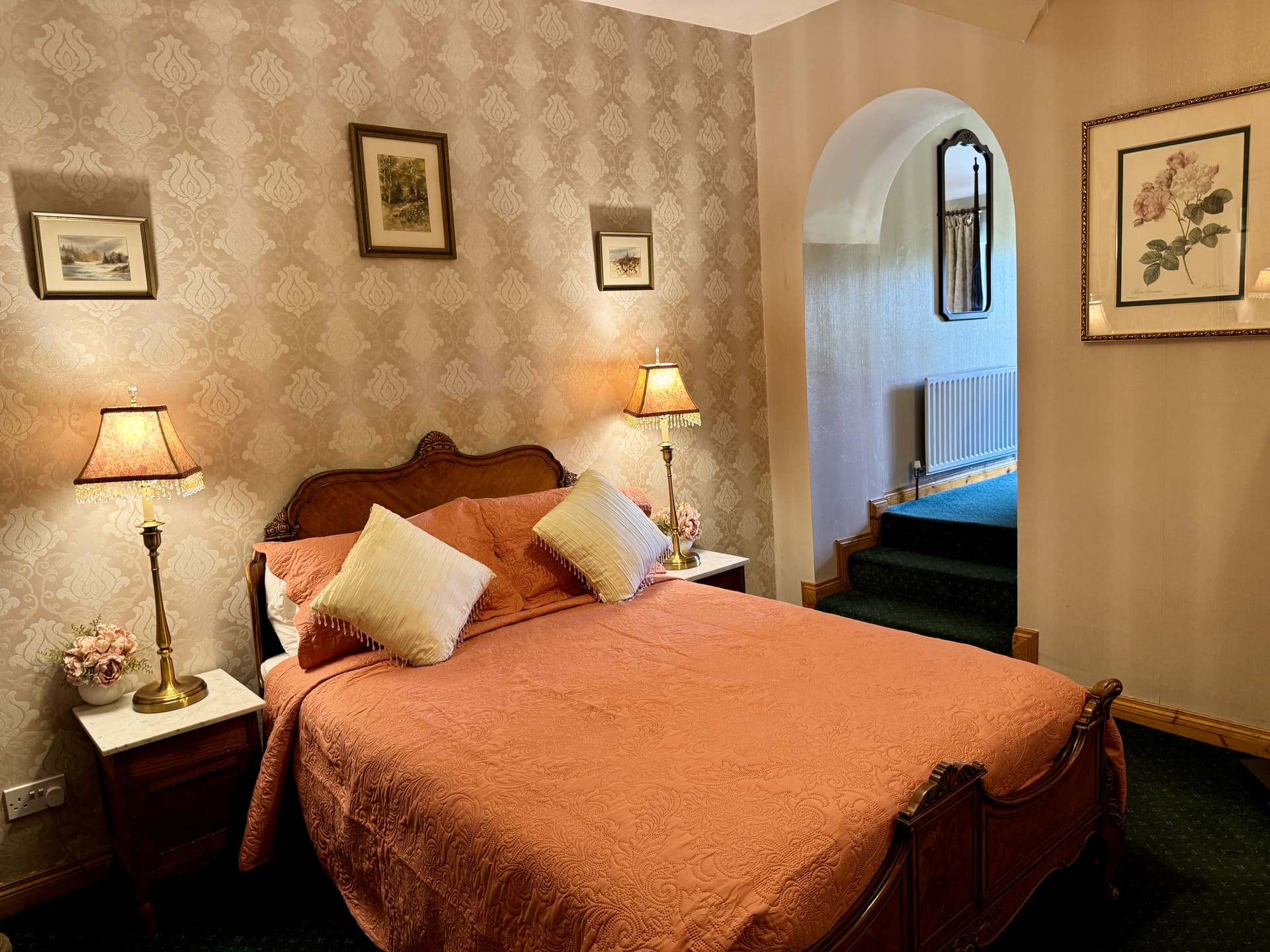 A bedroom with a peach bedspread and damask wallpaper