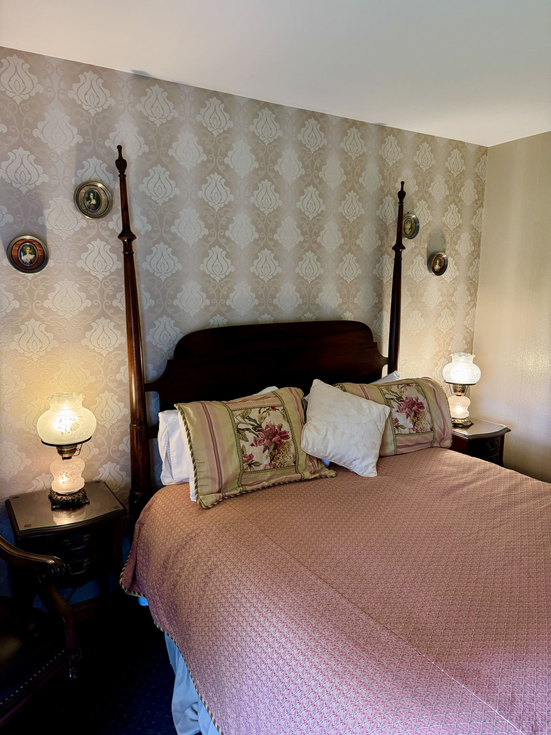 A four-poster bedroom with hurricane lamps either side