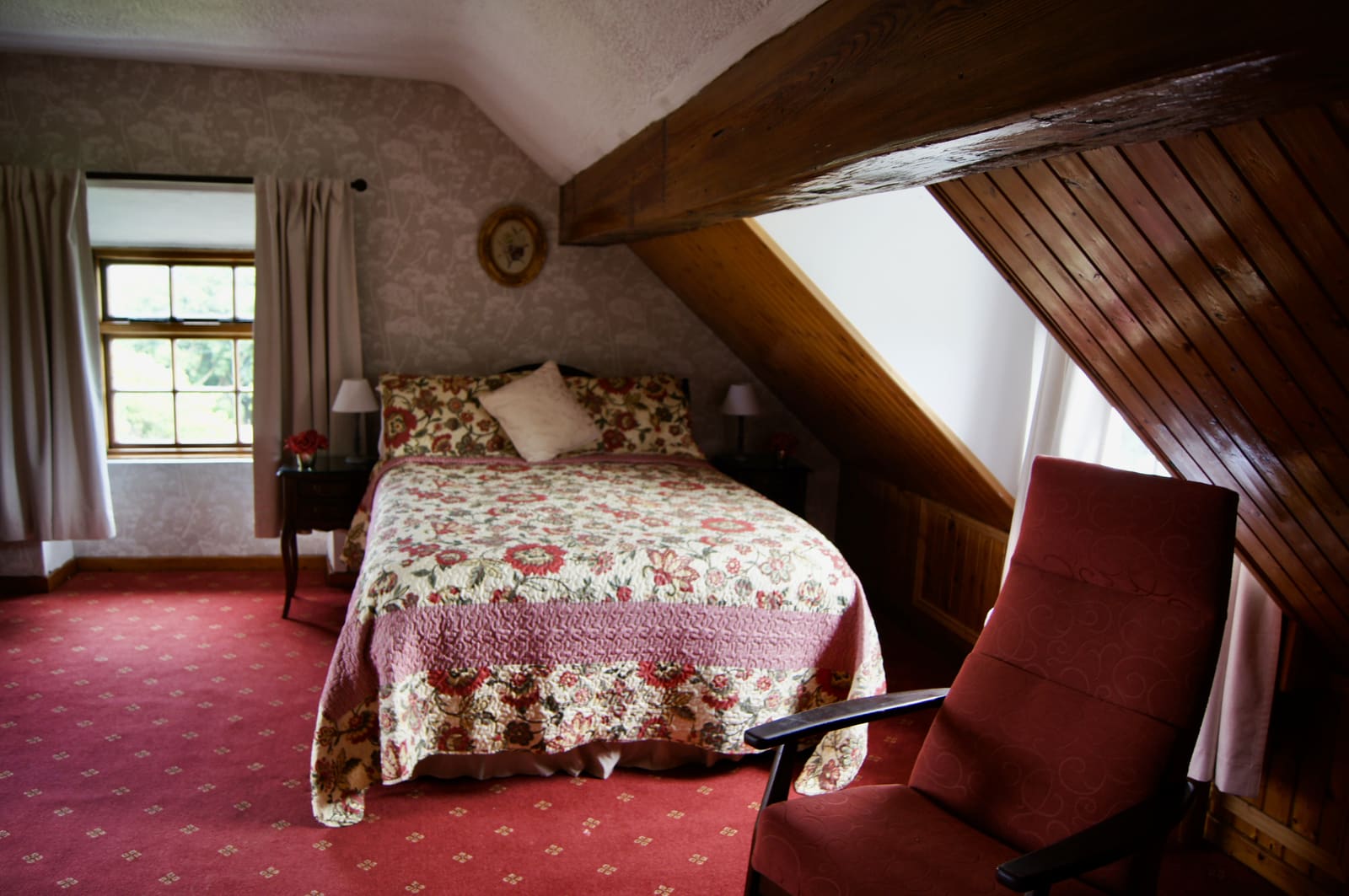 Triple Ensuite bedroom with floral bedding, red carpet, and sloped timber ceiling