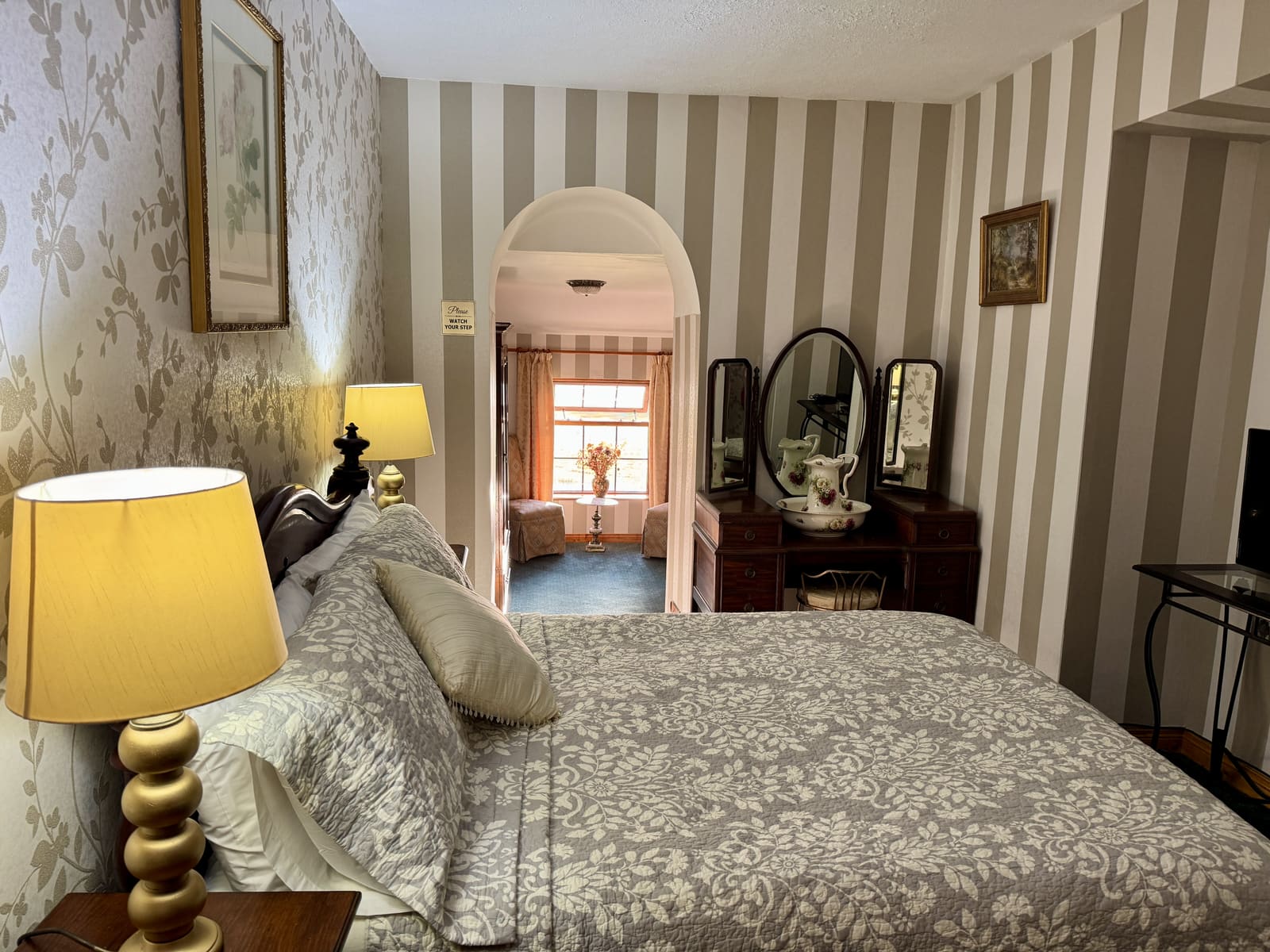Double Ensuite bed with striped wallpaper, bedside lamp, and dressing table