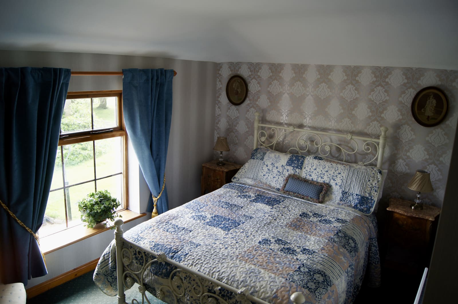 Family Ensuite bed beside a window with blue curtains and garden views