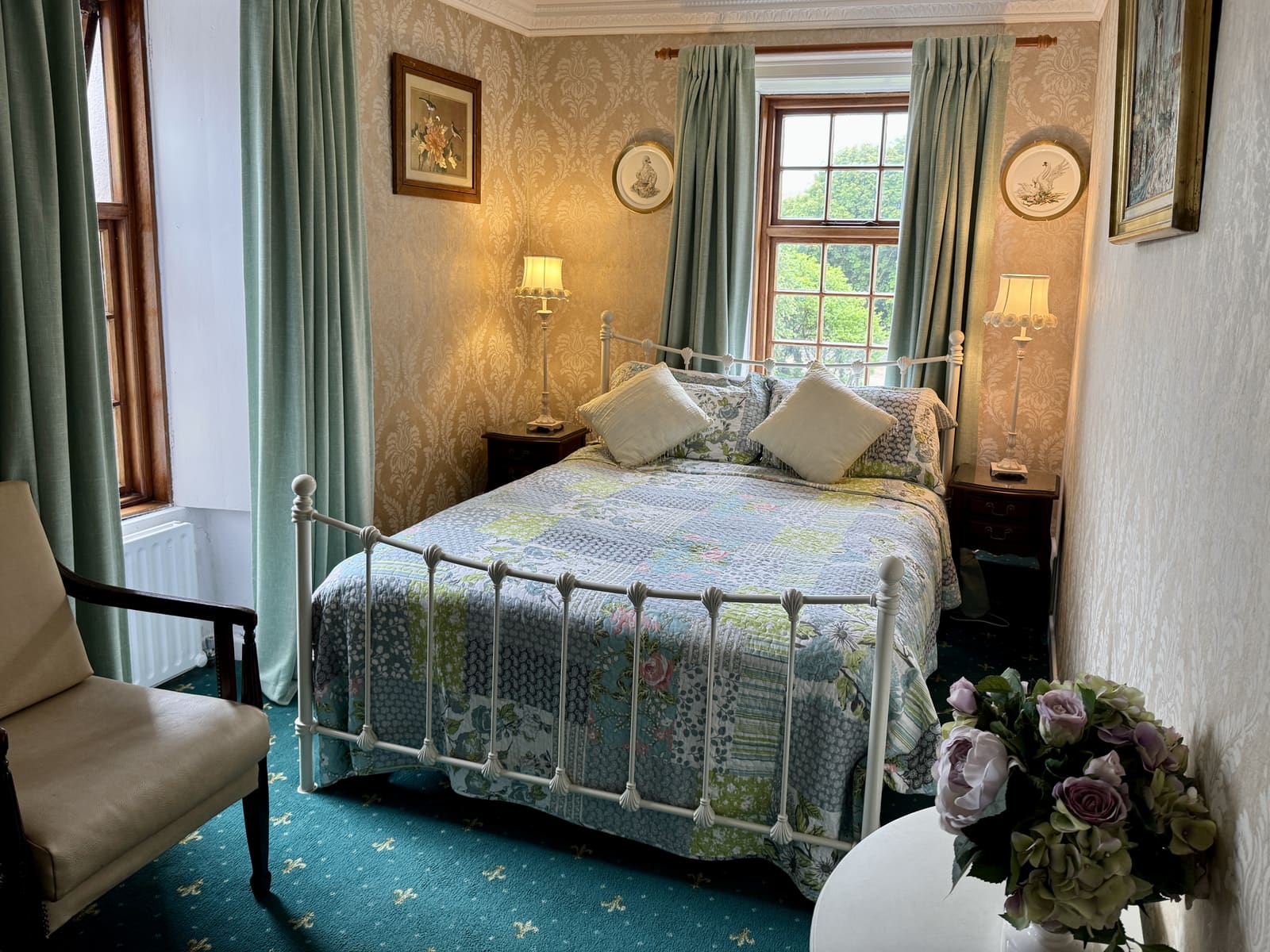 King Ensuite with a white metal bed, soft green curtains, and bedside lamps