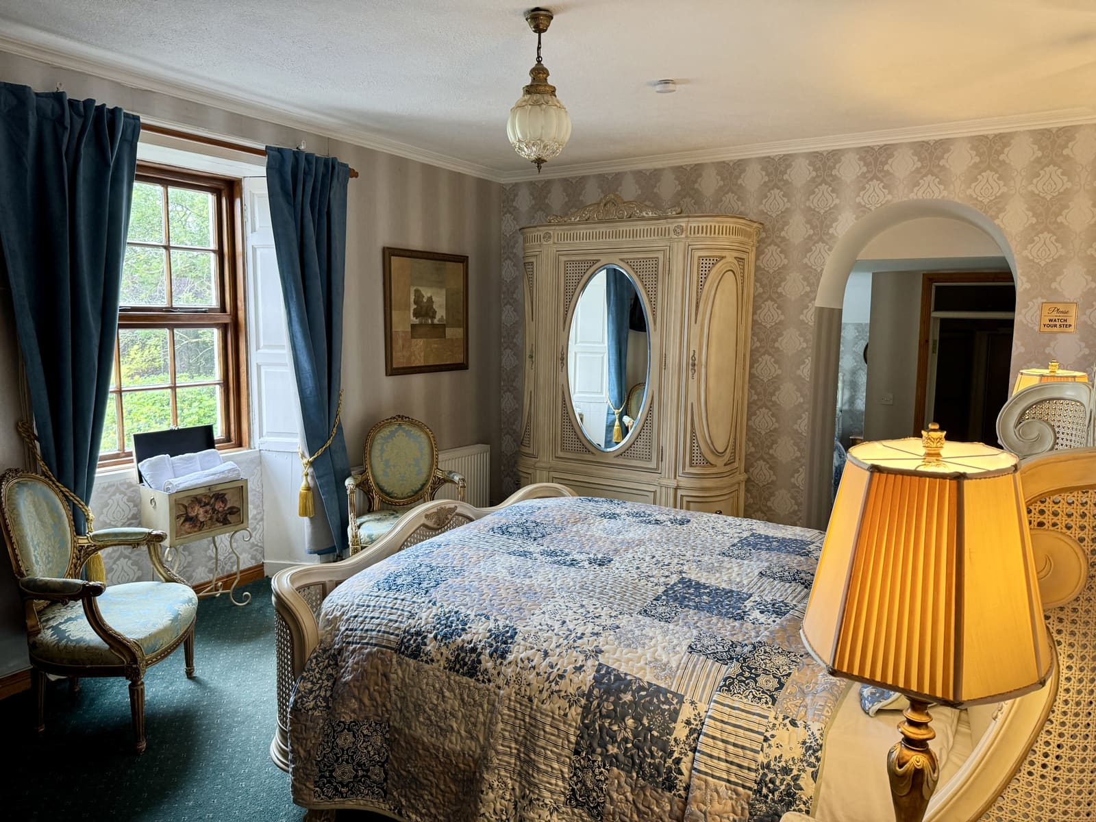 Wide view of the Family Ensuite with blue curtains, antique wardrobe, and patterned bedding